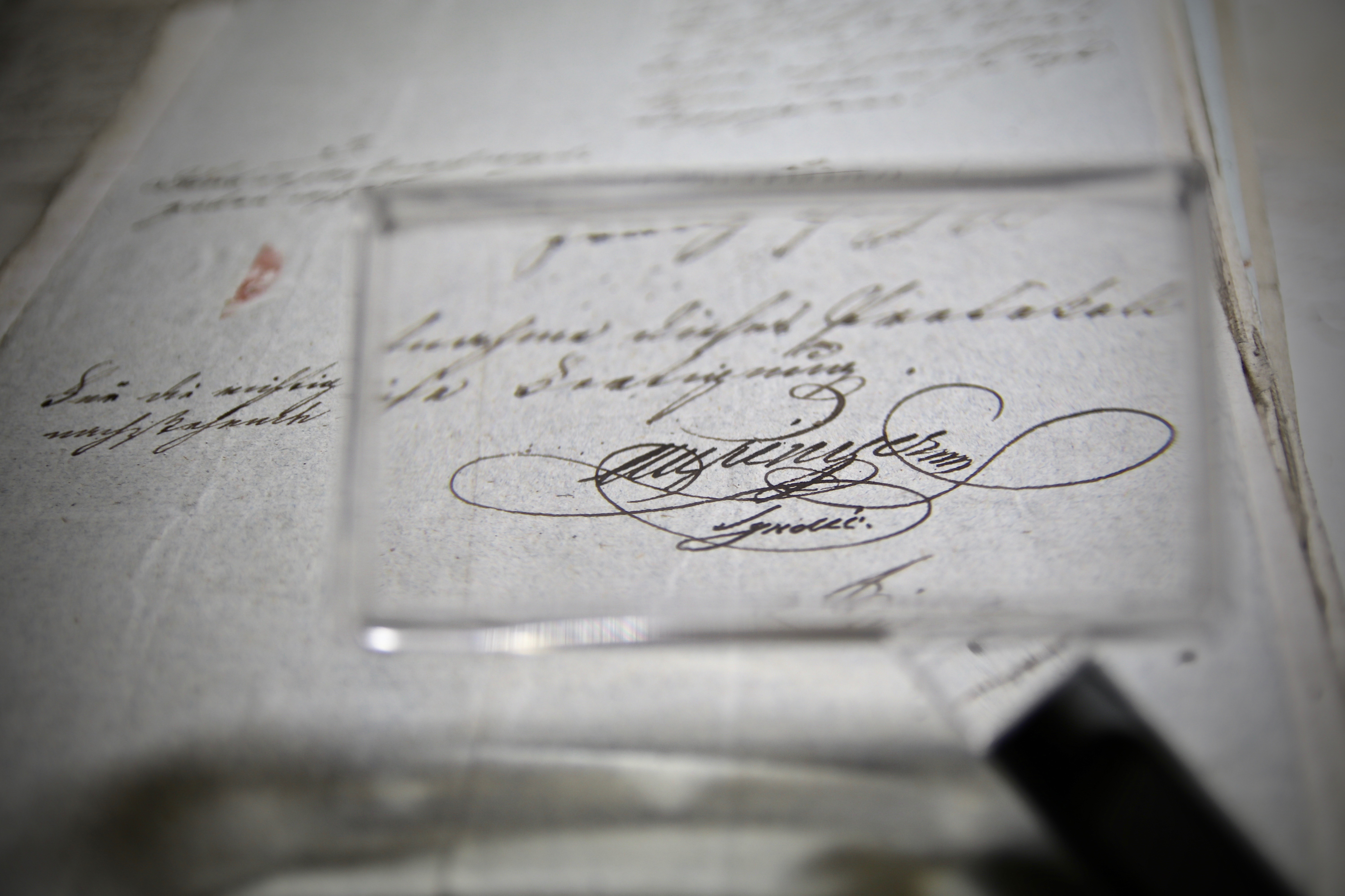 Blick durch eine Lupe auf die Seiten einer alten Schrift