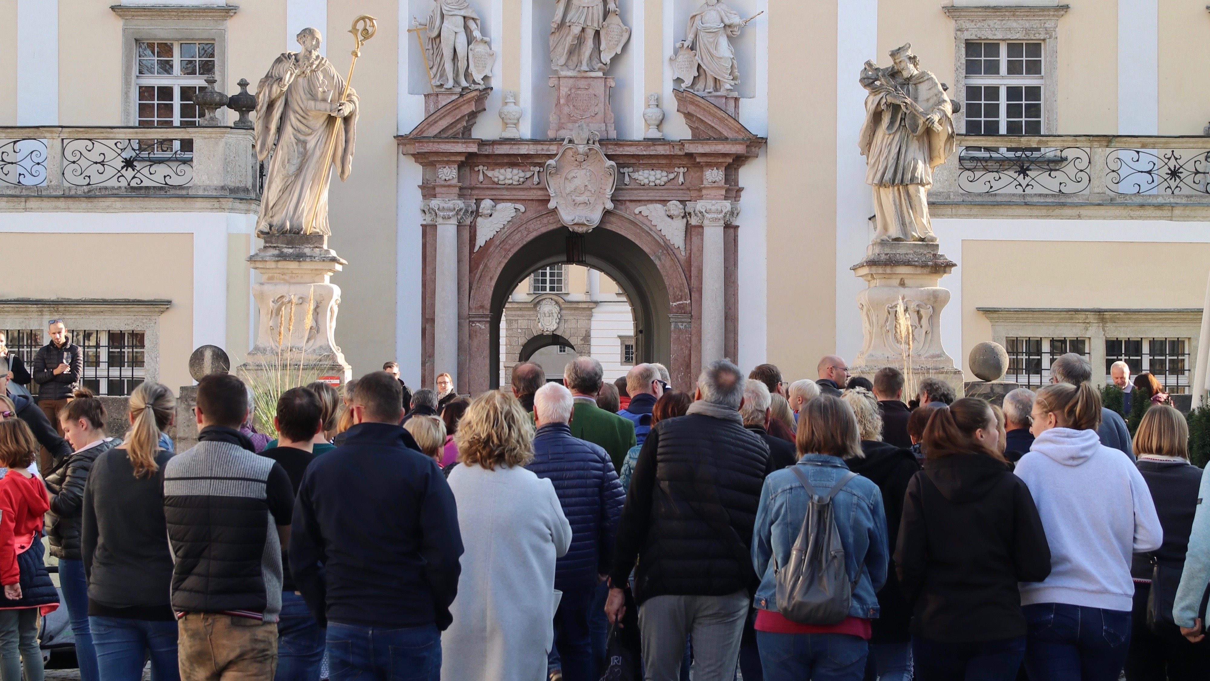 Menschenansammlung im äußeren Stiftshof mit Blick auf die Statue des Heiligen Benedikt