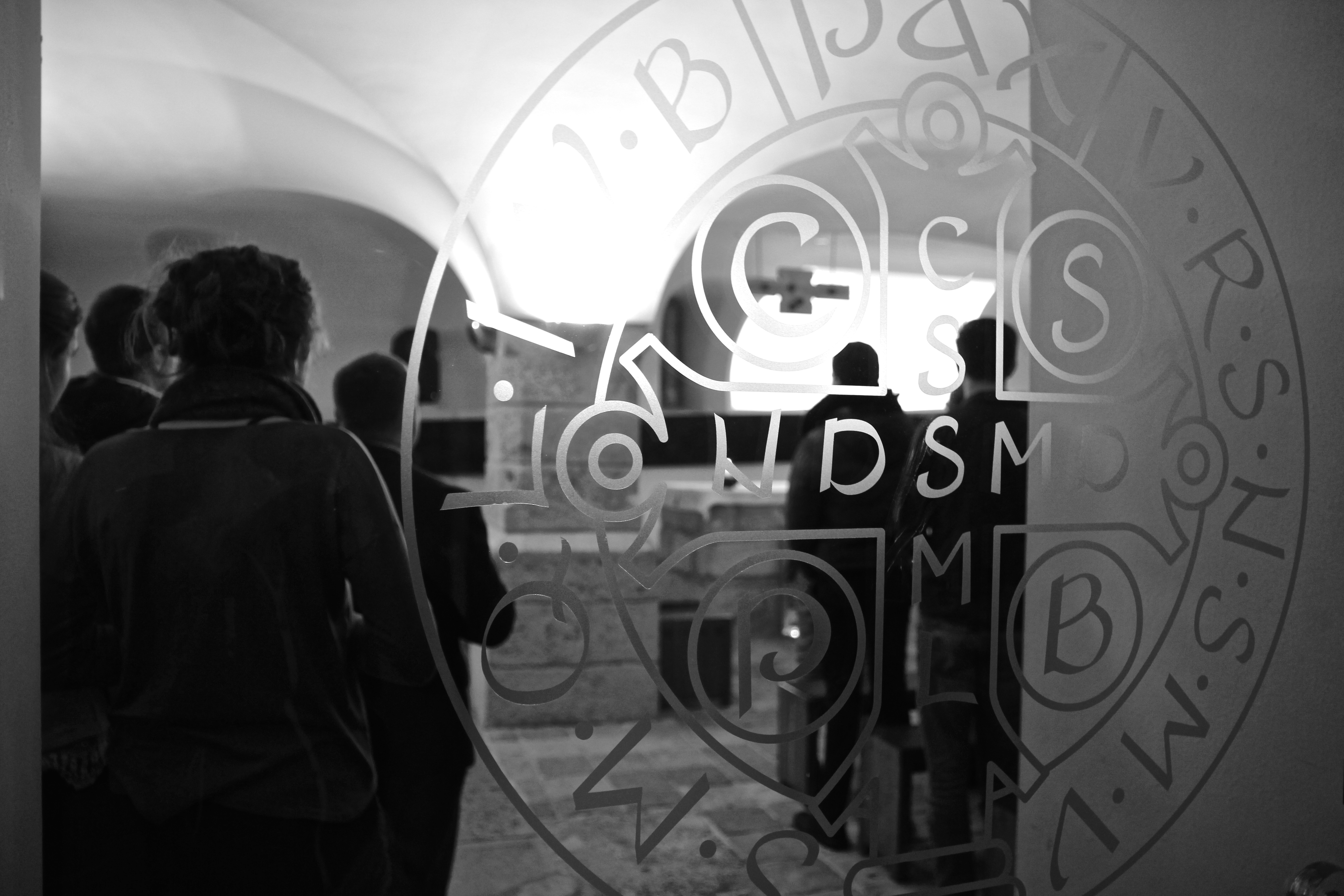 Schwarzweißaufnahme vom Blick durch die gläserne Eingangstür in die Michaelskapelle