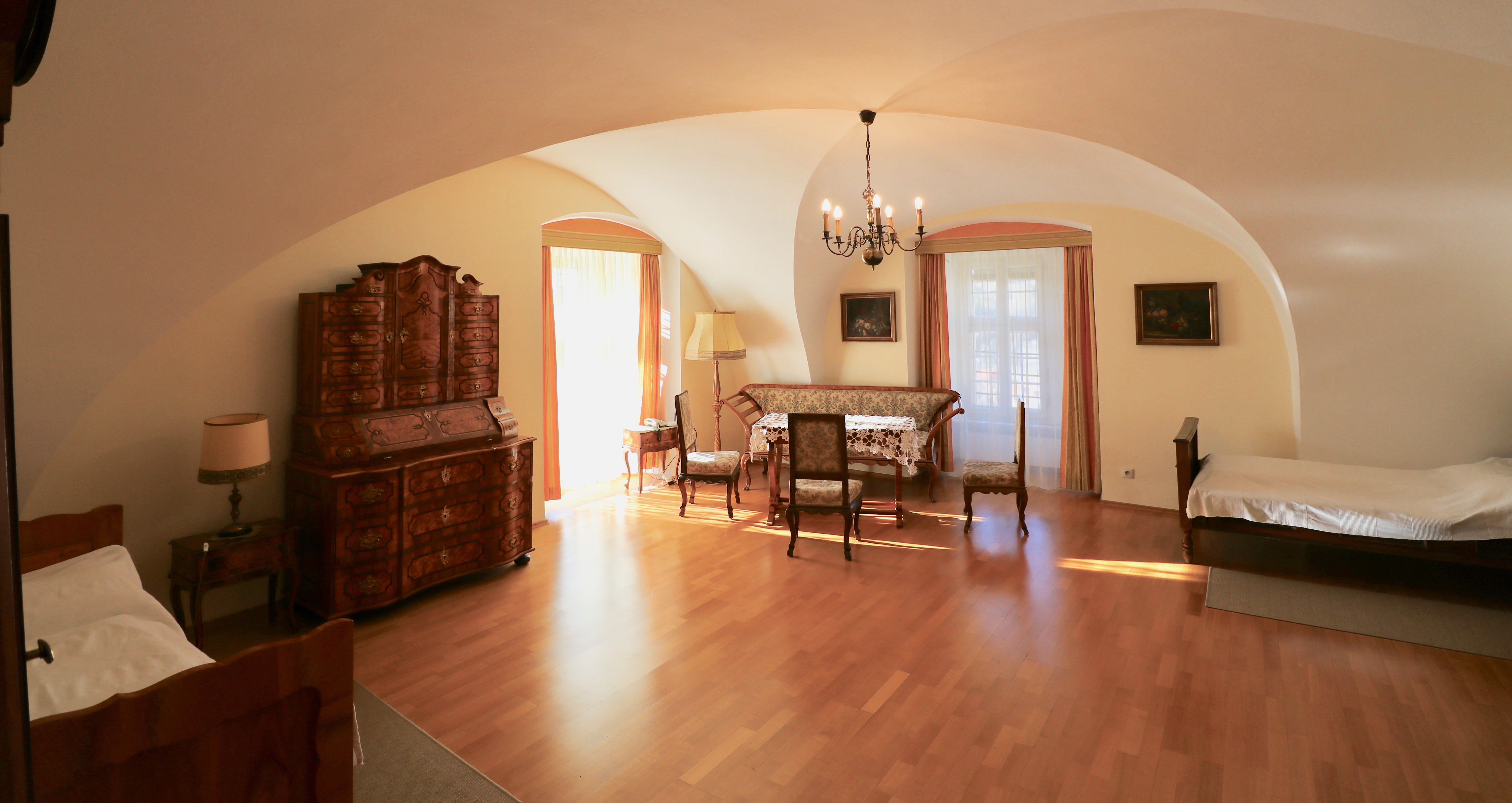 Geräumiges Zimmer mit zwei Einzelbetten, Holzkommode und Sitzgruppe im Jugendstil