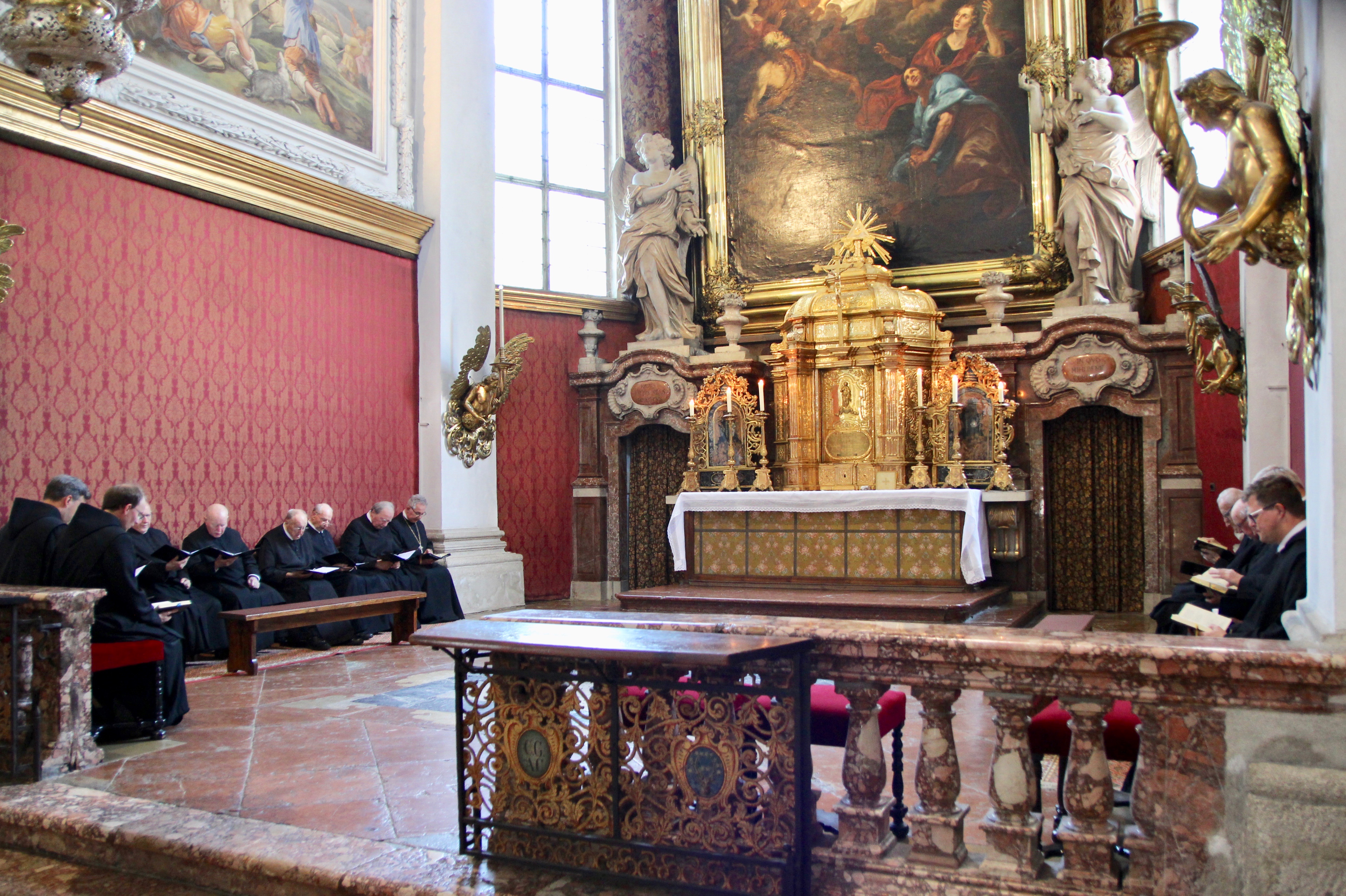 Die Mönchsgemeinschaft sitzt im Altarraum der Stiftskirche und liest aus deren Gebetsbücher