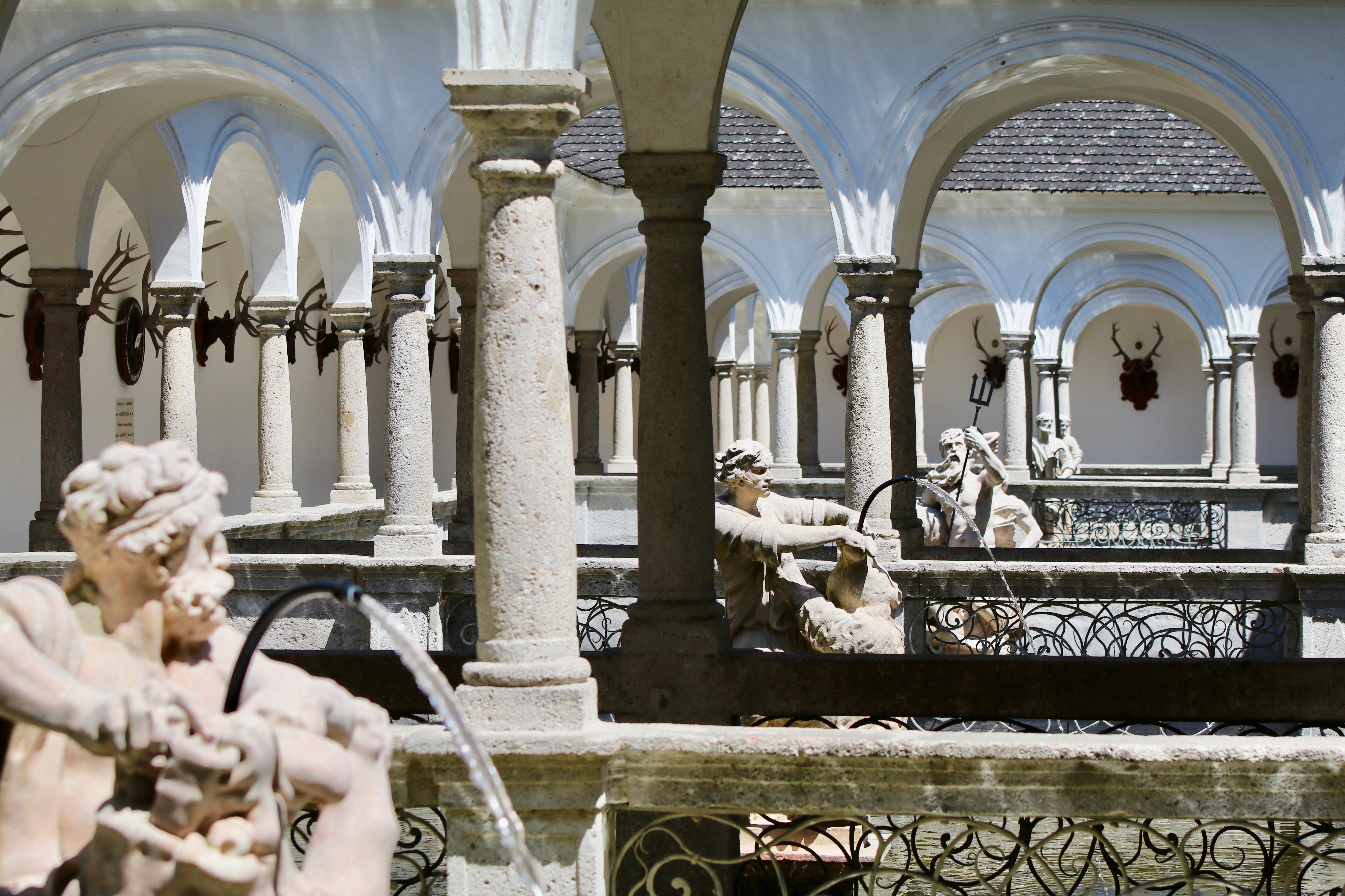 Blick durch die Steinsäulen in den offenen Gängen des Fischkalters. Steinskulpturen sprudeln frisches Wasser in die Fischbecken.
