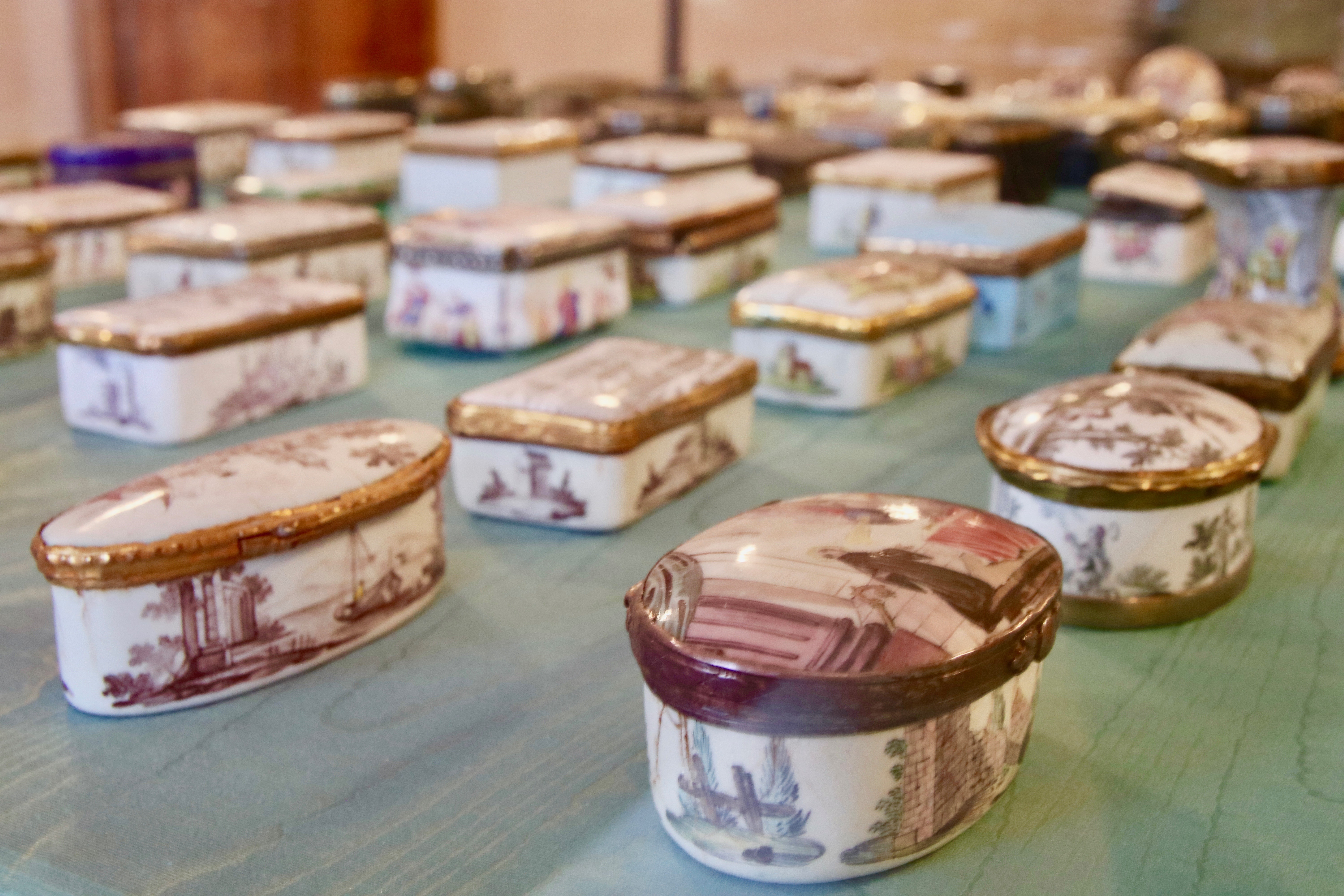 Dosen aus Metall, Holz oder Stein, bemalt mit Heiligen, einer Ansicht des Stiftes Kremsmünster, mit einem Vulkanausbruch, Portraits oder lustigen Szenen wie zum Beispiel kochenden Hunden in Küchenschürze