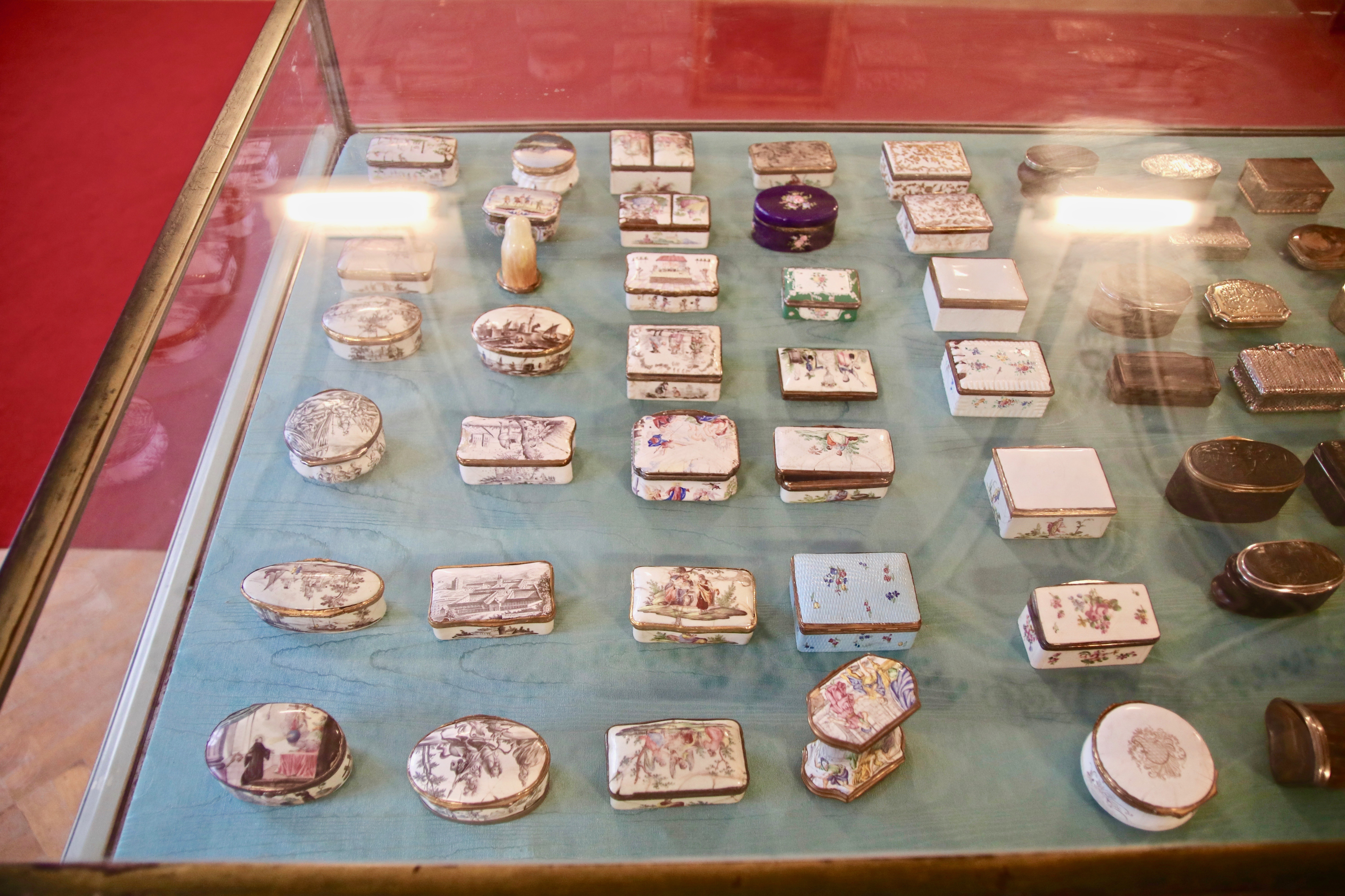 Viele kleine Blechschatullen mit Verzierungen in einer Tischvitrine