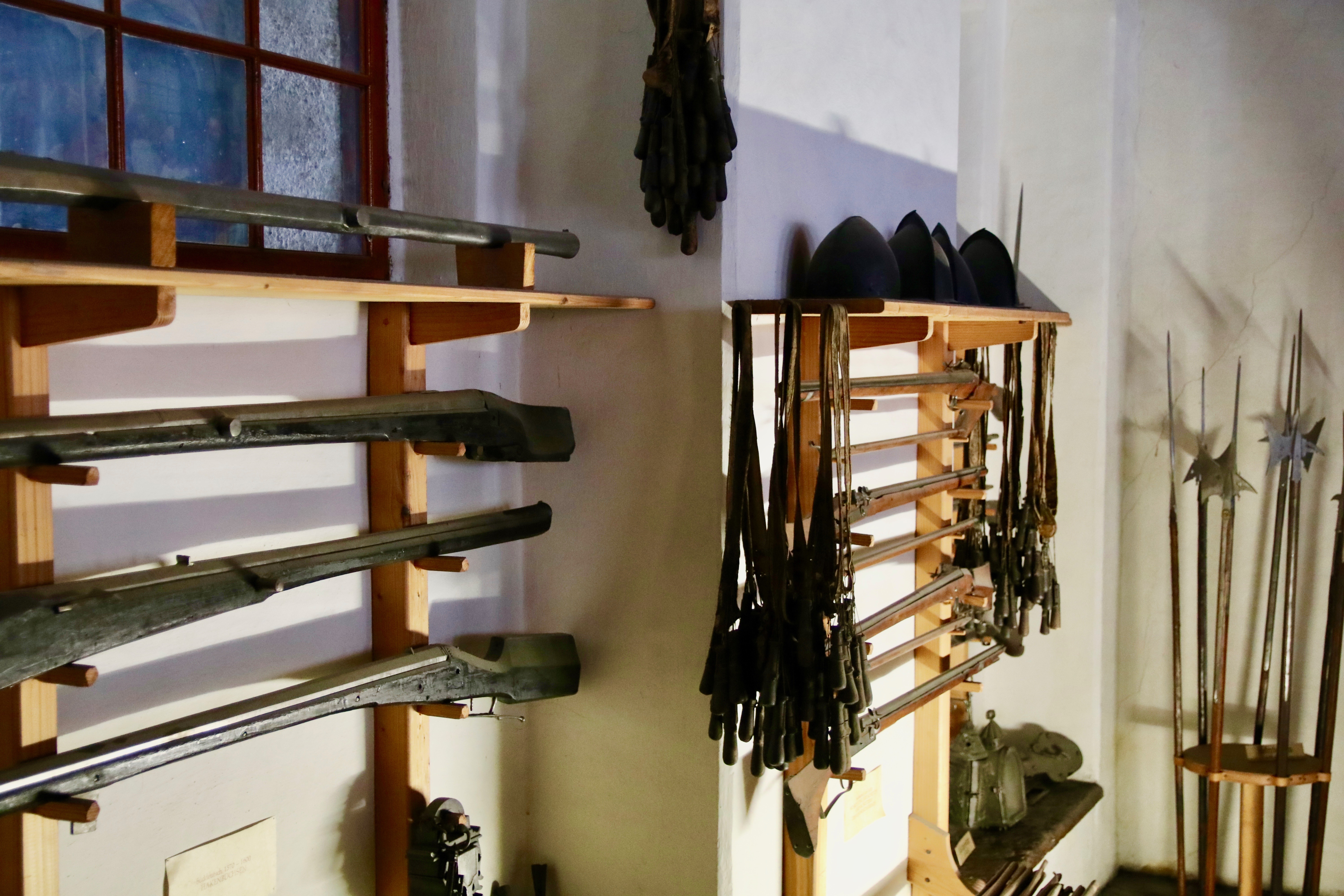 Mittelalterliche Schusswaffen und Speere in Wandregalen