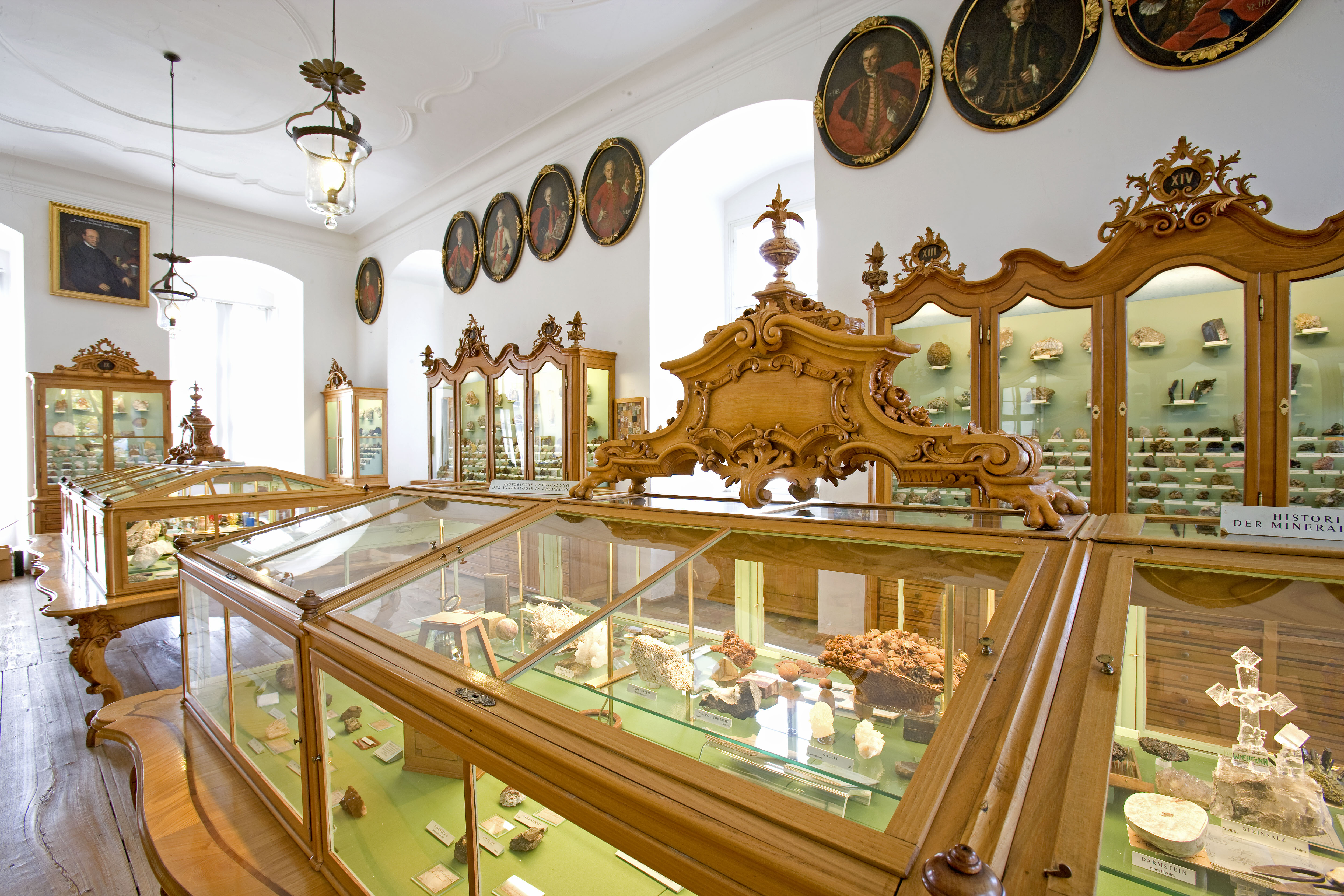 Goldene Glasvitrinen zeigen viele astronomisch interessante Gegenstände, an der Wand hängen viele kleine Portrait-Gemälde