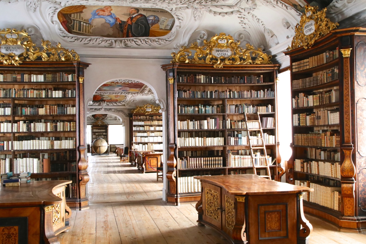 Eine große, prunkvolle Bibliothek mit hochwertigen Holzschränken und Goldverzierungen; auch die Decke ist verschnörkelt und mit Gemälden bemalt