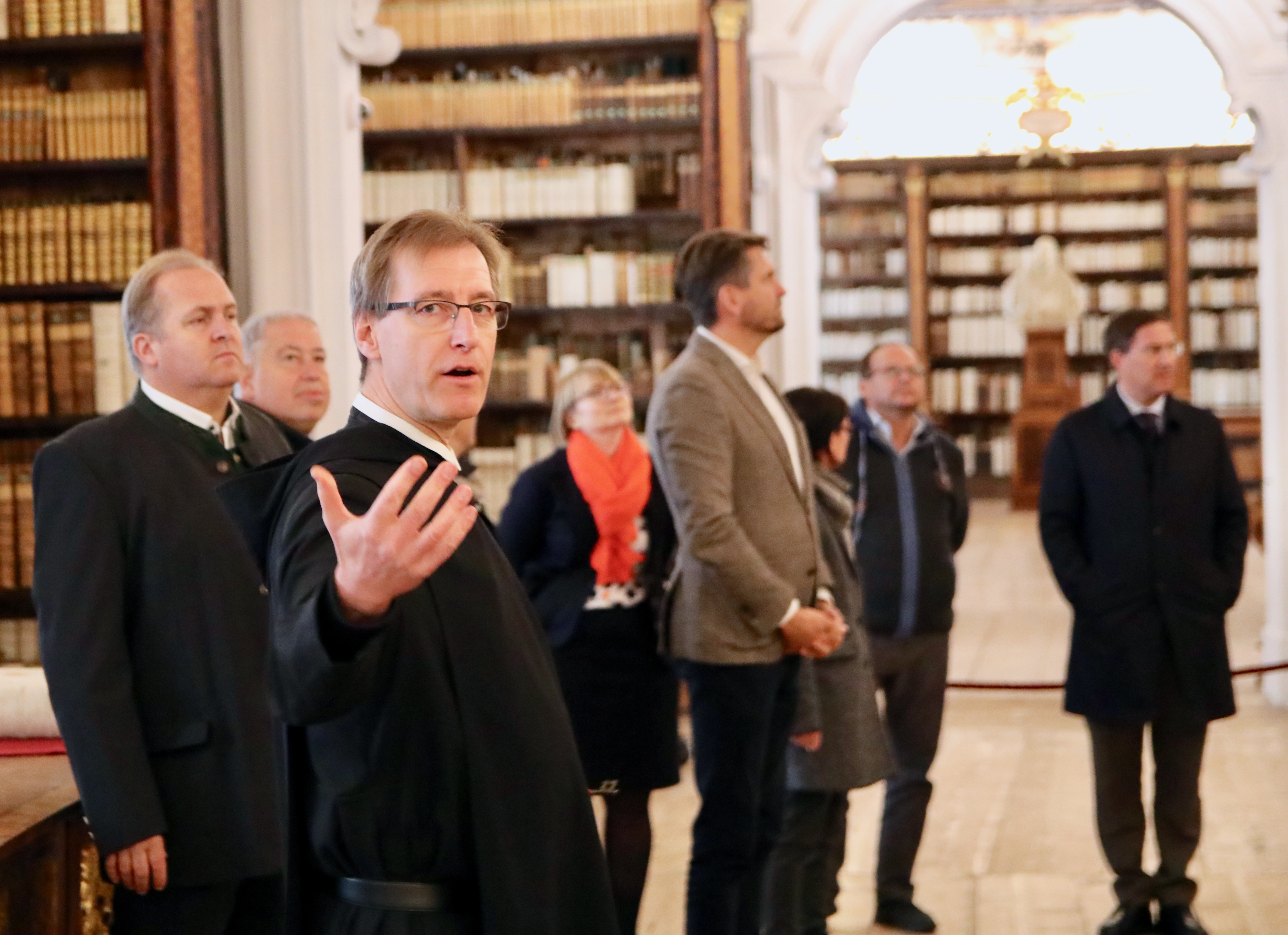 Ein Mönch gibt eine Führung durch die Bibliothek, die Gruppe bewundert den Raum