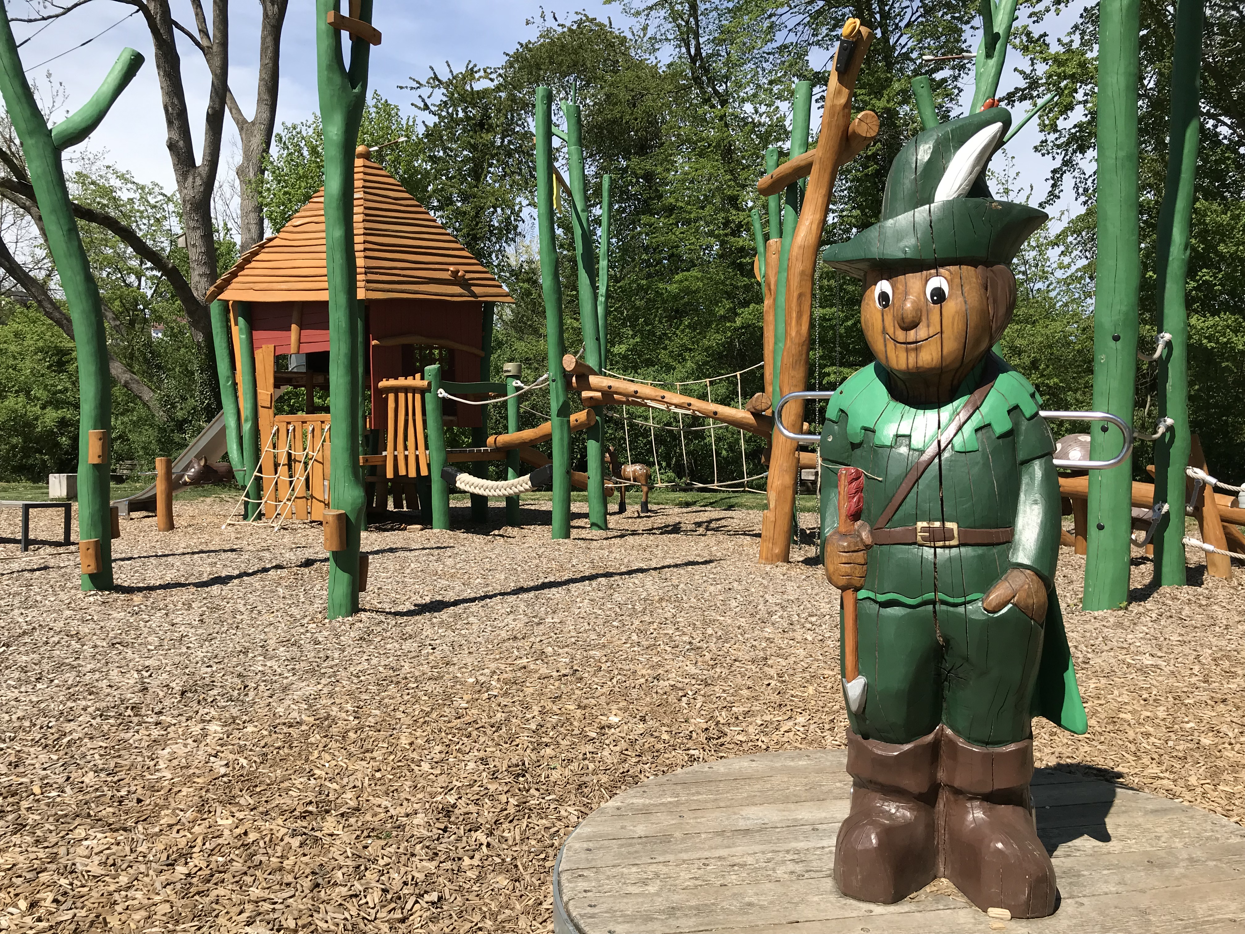 Ein Jäger als Holzfigur lädt ein zum Spielen im Klettergarten