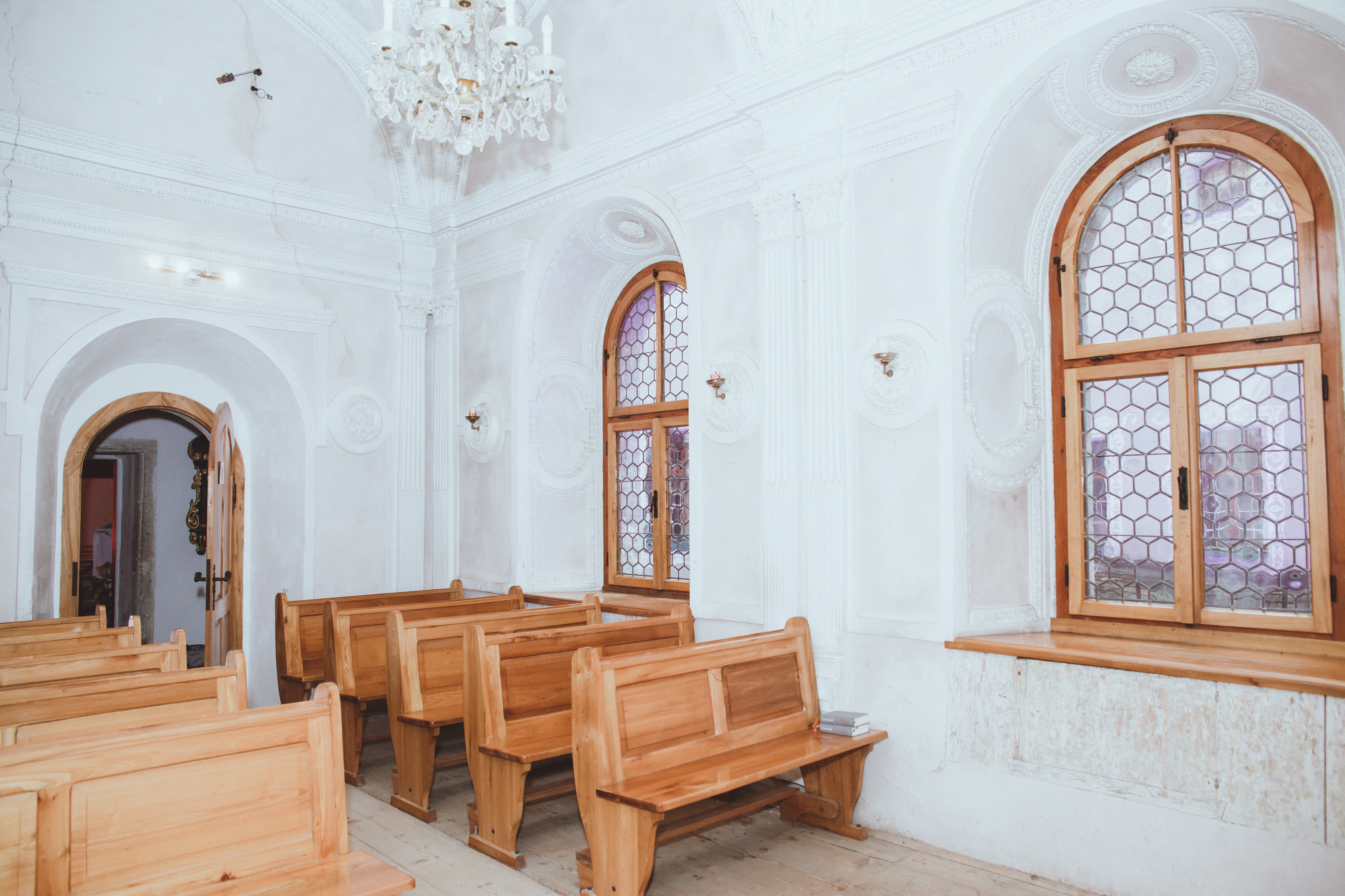 Pernsteiner Marienkapelle: Klarweiße Wände, frische Holzbänke und oben abgerundete Holzfenster mit angebrachten Eisengitter im Bienenwabenmuster