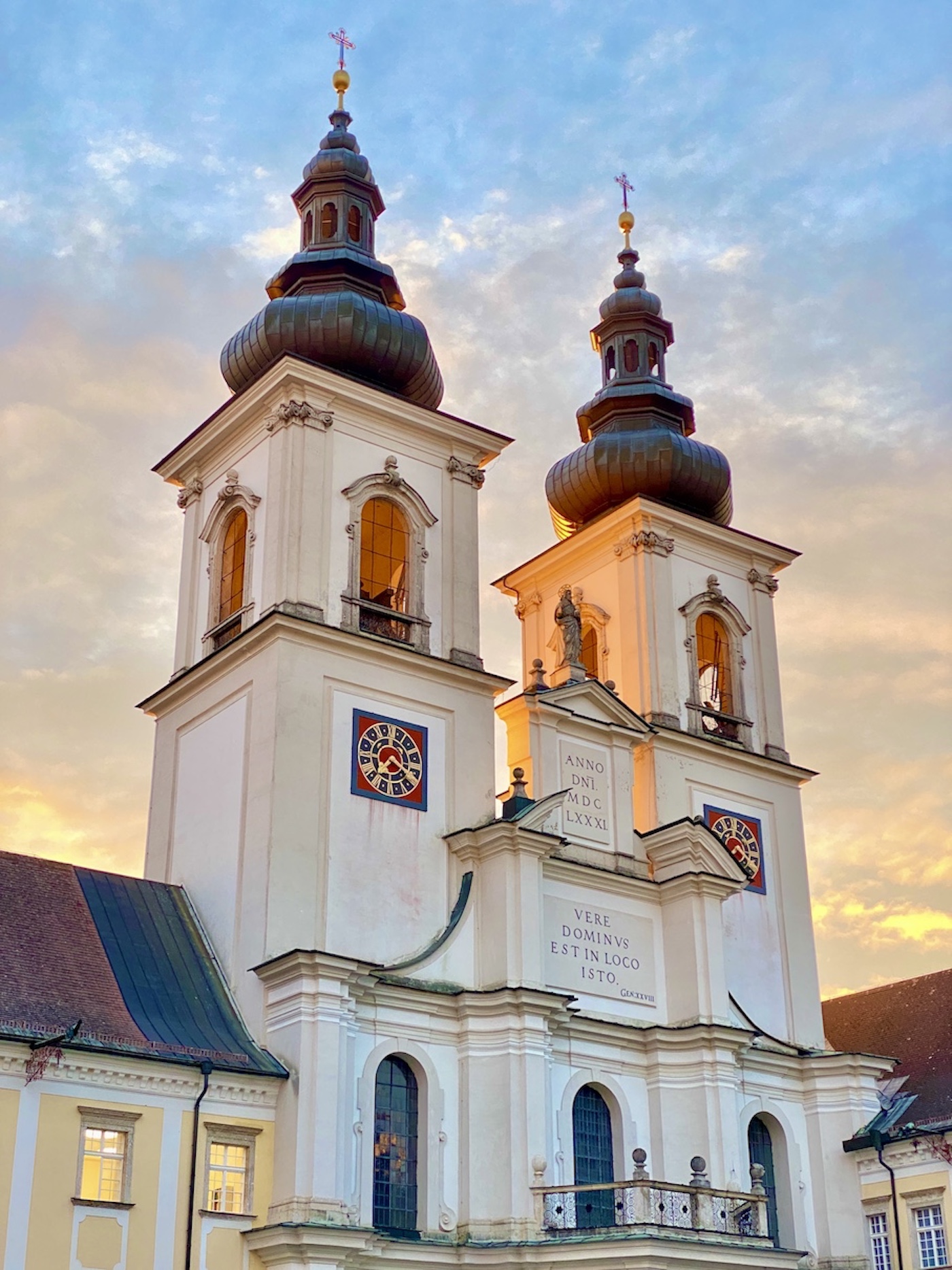 Aufnahme der beiden Kirchentürme der Stiftskirche im warmen Licht der Morgensonne vor der Renovierung; man erkennt sofort, wie die Fassade einer Renovierung bedarf; die Farbe der Kirchenuhren läuft auf dieser alten Aufnahme bereits ab