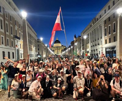 Eine Gruppe junger Leute in Rom mit österreichischer Flagge, im Hintergrund der Petersdom