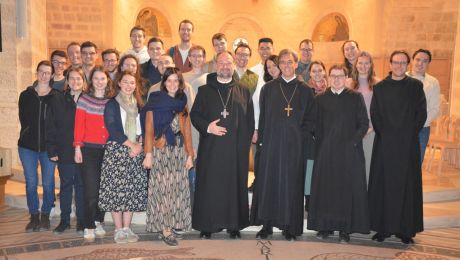 Gruppe von jungen Leuten mit zwei Äbten und zwei Mönchen in einer Kirche