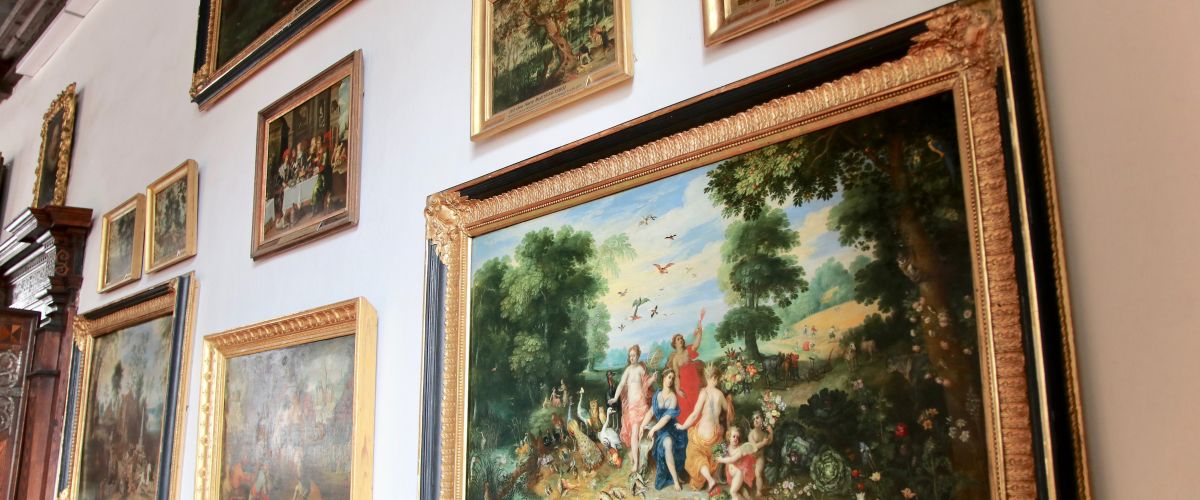 Mehrere Ölgemälde in schwarz-goldenem Rahmen an einer weißen Wand