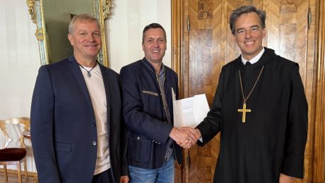 Drei Personen, zwei geben sich die Hand