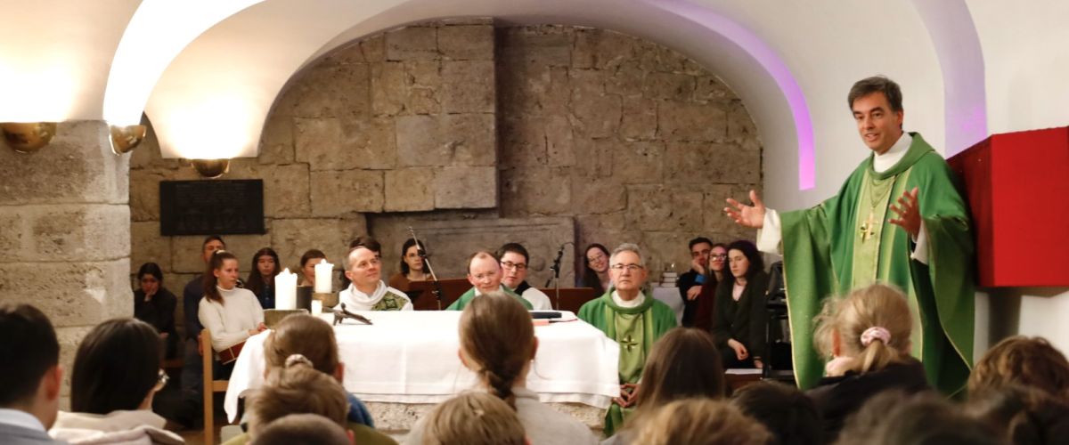 Blick aus der Menge der Jugendlichen während der heiligen Messe in Richtung Abt Bernhard, welcher mit Begeisterung und offenen Armen prädigt.