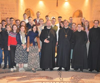 Gruppe von jungen Leuten mit zwei Äbten und zwei Mönchen in einer Kirche