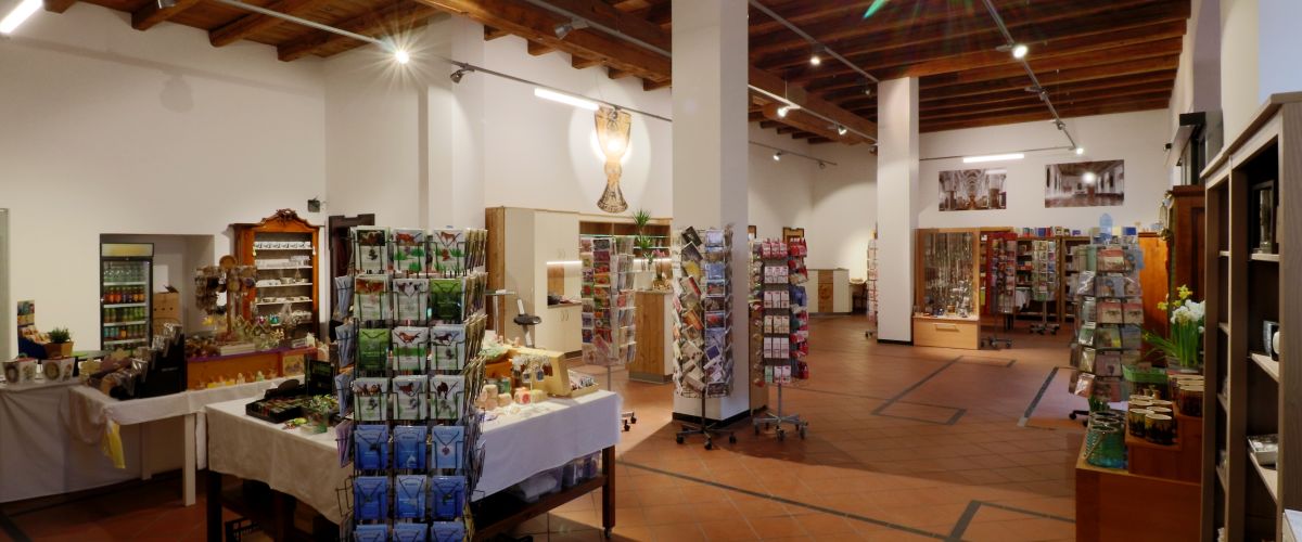 Einblicke in den Klosterladen mit seinem vielseitigen Produktsortiment, dem Tassilokelch als Abbildung an der Wand und der hohen Holzdecke