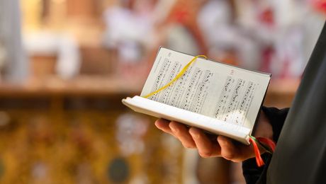 eine Hand hält ein aufgeschlagenes Gotteslob