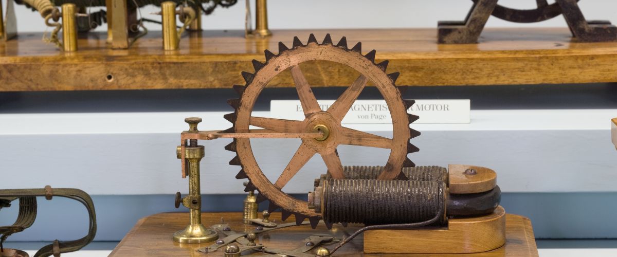 Ein Apparat mit großem Zahnrad und Magneten aufgebaut auf einer Holzplatte 