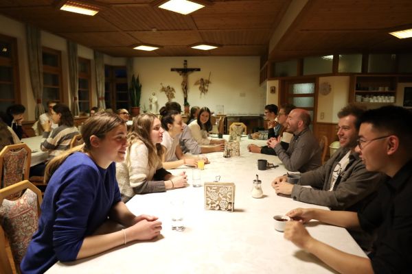 Viele junge Menschen bei Tisch: Es läuft die Vorgesprächsrunde beim Treffpunkt Benedikt. Im Bildhintergrund hängt ein großes Kruzifix.