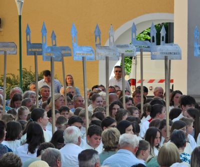 viele menschen halten Tafeln mit Kichenmodellen aus Metall, auf jeder steht der Name einer Pfarrkirche