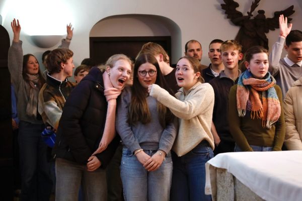 Heilige Messe beim Treffpunkt Benedikt: Es wird gesungen und mit ausgestreckten Händen hochgelobt. Drei Jugendliche Mädls albern herum, indem sie sich ein Mikrofon aus Luft vorhalten.