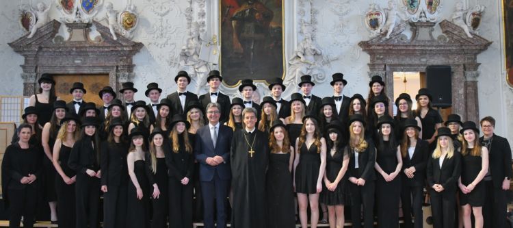 Gruppenfoto in einem Festsaal mit circa 50 jungen Personen festlich schwarz gekleidet mit Zylinder