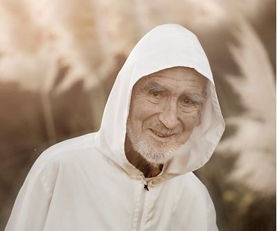 Porträt von Bruder David Steindl Rast, mit grauem Bart, weißer Jacke und weißer Kaputze