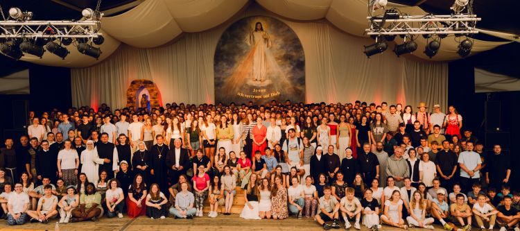 Abschlussfoto aller Beteiligten des Jugendtreffens im Stift Kremsmünster auf der Bühne im Zelt mit Jesus Bild und Text: "Jesus, ich vertraue auf dich"