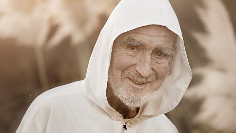 Porträt von Bruder David Steindl Rast, mit grauem Bart, weißer Jacke und weißer Kaputze