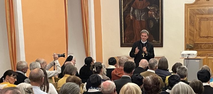 ein Redner und sitzende Personen, die bei einem Vortrag zuhören