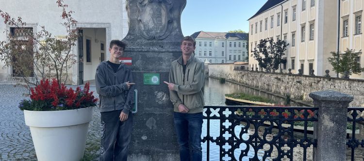 Zwei Schüler vor einem Wassergraben zeigen auf einen QR-Code