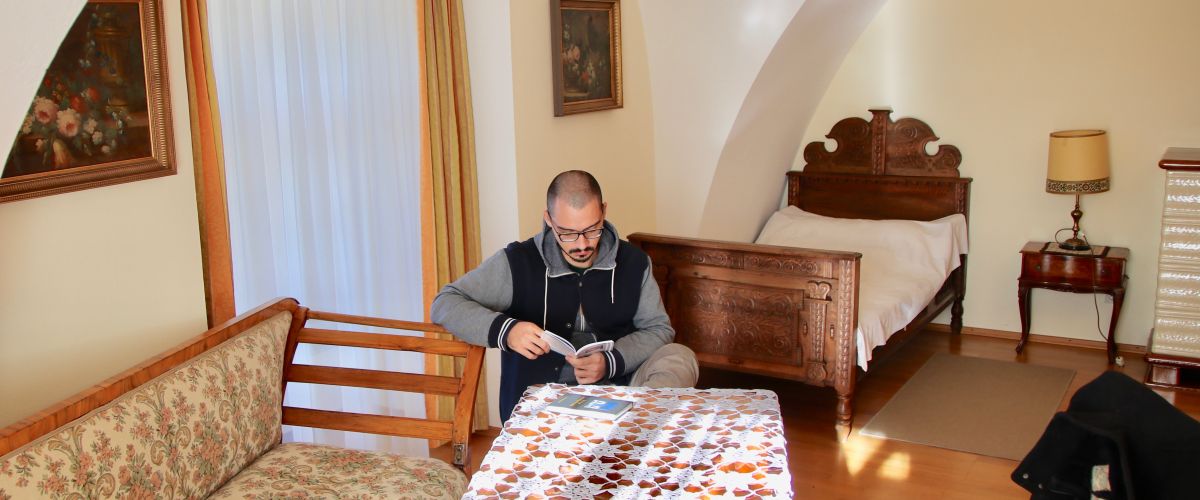 Ein junger Mann sitzt in seinem Gästezimmer und liest