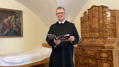 Mönch in schwarzem Ordensgewand in einem Gastzimmer