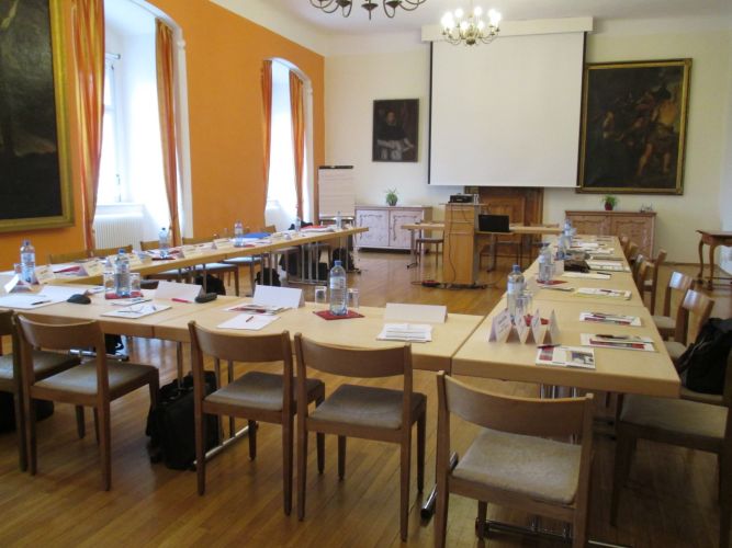 In U-Form aufgestellte Tische laden ein zur gemeinsamen Besprechung an der Projektor-Leinwand