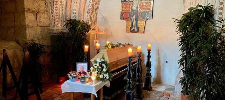 Aufgebahrter Sarg mit Kerzen und Blumen