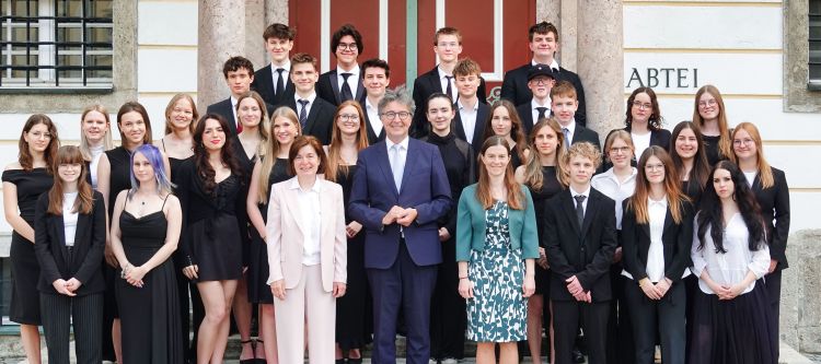 Maturantinnen und Maturanten festlich gekleidet vor einem Portal