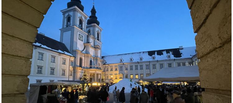 Blick auf großen Hof mit beleuchteten Ständen bei Dämmerung