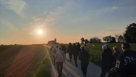 Gruppe von Personen, die bei Sonnenuntergang zu einer Kirche wandert