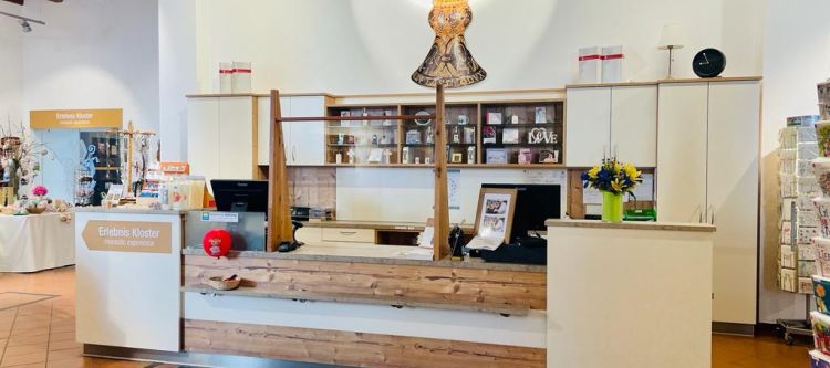 Verkaufstheke aus hellem Holz, an der Wand dahinter die Abbildung des Tassilo-Liutpirc-Kelches
