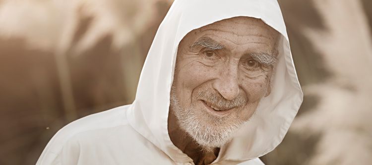 Porträt von Bruder David Steindl Rast, mit grauem Bart, weißer Jacke und weißer Kaputze