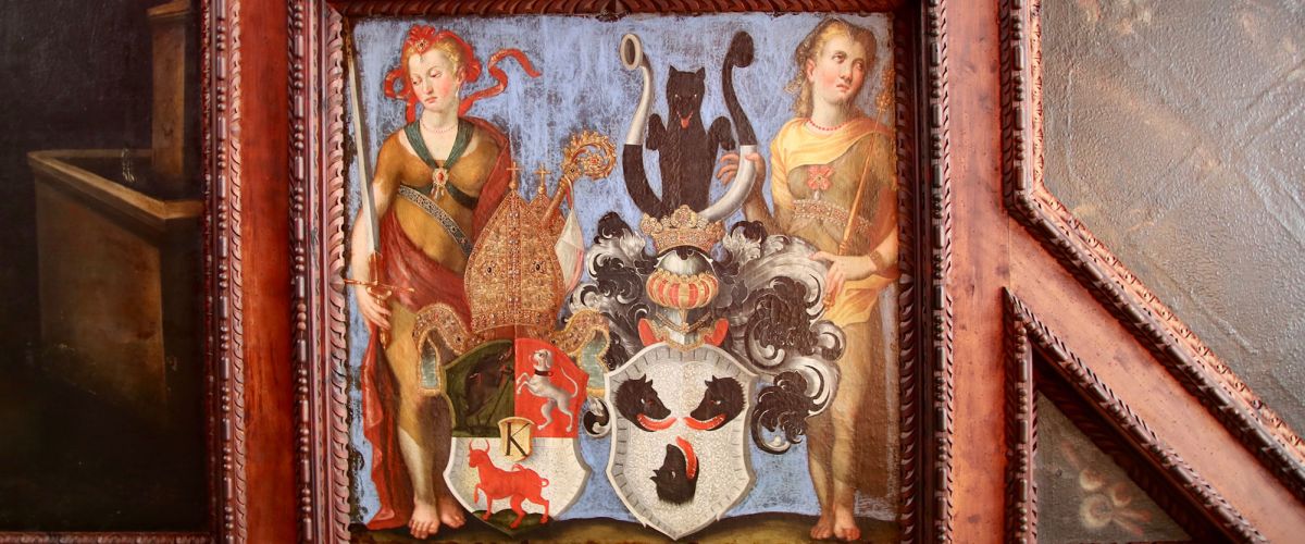 Ein mittelalterliches Bild: zwei Menschen und zwei Wappen in bunten Farben, die Wappen enthalten ein Wildschwein, einen Hund und einen Stier sowie drei Drachenköpfe mit roten Zungen