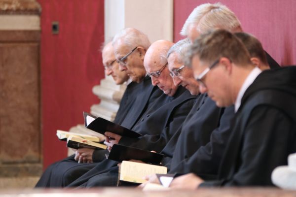 Mehrere Mönche blicken in deren Bücher und beten