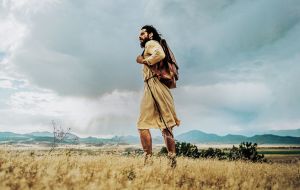 Jesus in einem Leinengewand und einem Lederrucksack um die Schulter in der Wüste, aus der Filmserie The Chosen