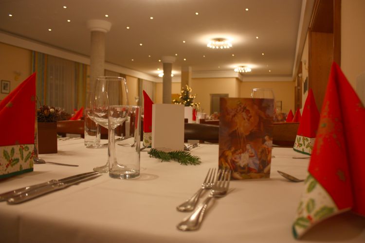 Foyer im Theater: Blick durch einen gedeckten Tisch im schicken Ambiente des Raumes. Kleine Lichtpunkte verzieren die weiße Akustikdecke. Steinerne Stehsäulen geben dem Raum Ordnung.