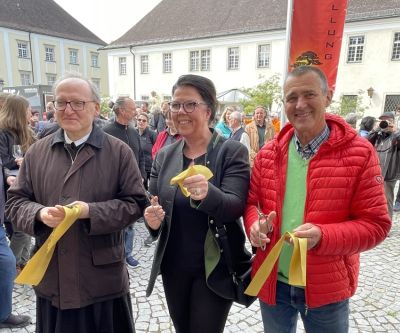 Drei Personen halten ein Band