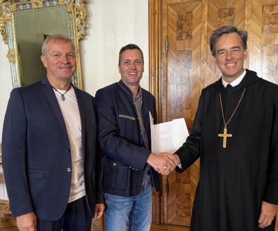 Drei Personen, zwei geben sich die Hand