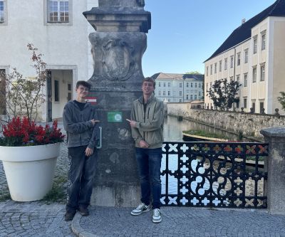 Zwei Schüler vor einem Wassergraben zeigen auf einen QR-Code