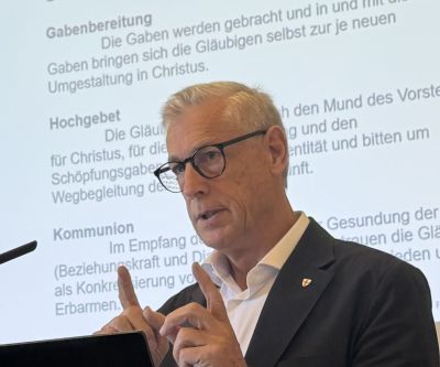 Porträt von Professor Volgger bei Vortrag, im Hintergrund Schrift auf eine Leinwand projeziert